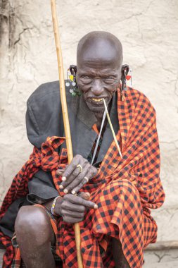 Aynı, Tanzanya, 4 Haziran, 2019: eski Masai adam dinlenme ve ağaç dalı ile dişlerini Temizleme