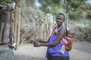 Aynı, Tanzanya - 4 Haziran 2019: Sırtında bebeği olan Maasai kadın