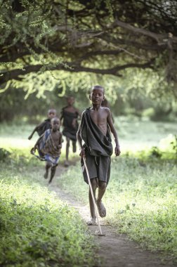 Aynı, Tanzanya - 4 Haziran 2019: Siyah giyinmiş Maasai erkekleri, onları hayatlarının bir sonraki aşamasına götüren 'geçiş hakkı' seremonisine hazır. Ertesi sabah sünnet edildiler ve maasai savaşçısı oldular.