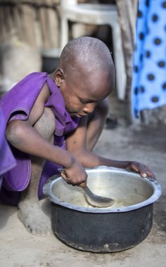 Aynı, Tanzanya - 4 Haziran 2019: genç Maasai kız o daha fazla yiyebilirsiniz böylece pot artıkları kazıma
