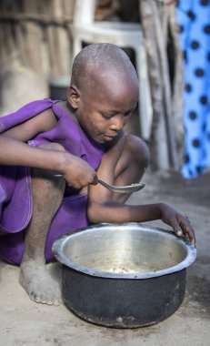 Aynı, Tanzanya - 4 Haziran 2019: genç Maasai kız o daha fazla yiyebilirsiniz böylece pot artıkları kazıma