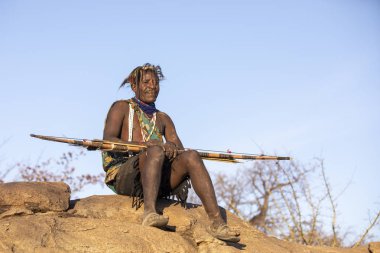 Eyasi Gölü, Tanzanya, 11 Eylül 2019: Hadzabe adamı yay ve okla dinleniyor