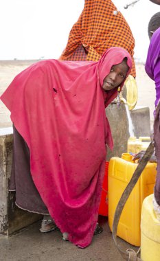 Arusha, Tanzanya, 8 Eylül 2019: Bir kuyudan su getirmek için elinde su kabıyla savanda yürüyen maasai kadınları