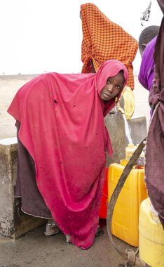 Arusha, Tanzanya, 8 Eylül 2019: Bir kuyudan su getirmek için elinde su kabıyla savanda yürüyen maasai kadınları