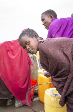 Arusha, Tanzanya, 8 Eylül 2019: Bir kuyudan su getirmek için elinde su kabıyla savanda yürüyen maasai kadınları