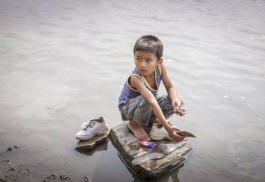 Chittagong, Bangladeş, 25 Şubat 2016: Bangladeşli çocuk ayakkabılarını nehirde yıkıyor