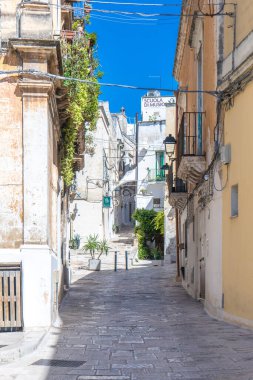 Güney İtalya 'da mavi bir gökyüzünün altındaki tarihi merkezde taş sokaklar ve Akdeniz balkonları arasında binaların bir görüntüsü. Grottaglie bir seramik şehridir..