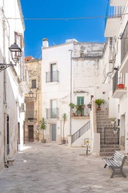 Güney İtalya 'da mavi bir gökyüzünün altındaki tarihi merkezde taş sokaklar ve Akdeniz balkonları arasında binaların bir görüntüsü. Grottaglie bir seramik şehridir..
