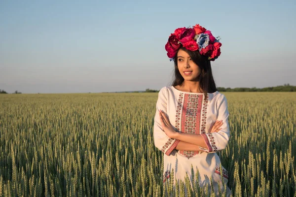 Geleneksel Ukrayna nakış giysileri ve çiçek desenli çelenk giymiş güzel Hintli genç bir kadın sahada duruyor, uzaklarda hayal kuruyor ya da düşünüyor, güzel etnik bir kadın doğada poz veriyor. 