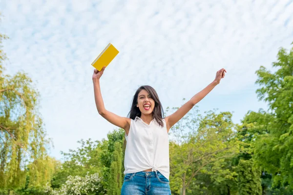 Mutlu Hintli kız. Zaferin işareti. Gökyüzünün arka planında beyaz bulutlar var. Düşük açı görünümü