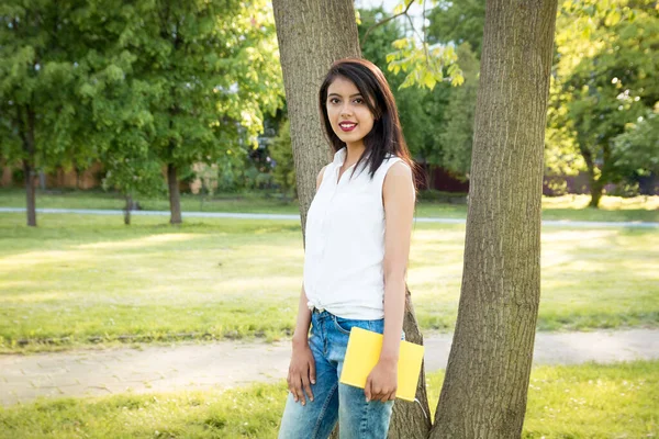 Young Beautiful Indian Girl Standing Park Tree Holding Yellow Notebook — Stock Photo, Image