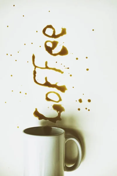 白い背景の上にコーヒーで書かれた単語コーヒーと横たわっているコーヒー カップ — ストック写真