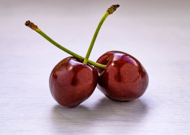 Beyaz ahşap masa üstünde yeşil kuyruk ile kırmızı çilek.