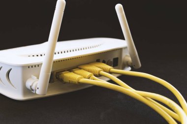 Beyaz bir modem takılı sarı ağ kabloları.
