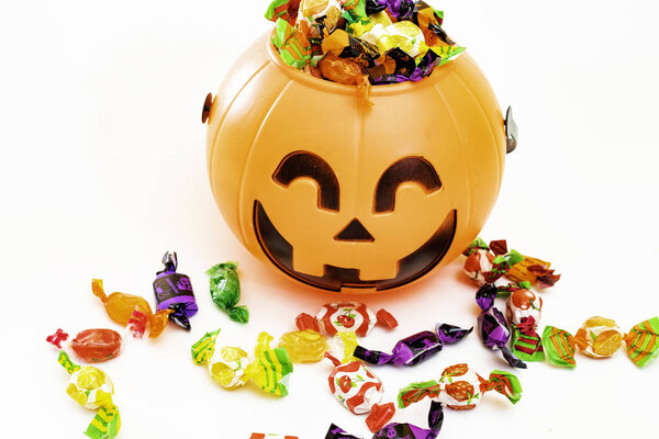 Halloween pumpkin with candies by the side, with white background.