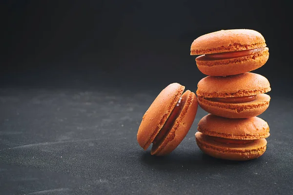 Siyah bir zemin üzerine portakal portakal macarons.