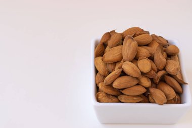 Çiğ badem beyaz tabakta. Badem bir arka plan ile.