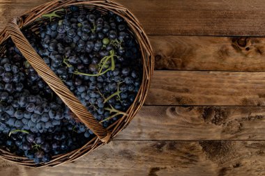 Hasır sepet dolu bir rustik çam ahşap masa üzerinde şarap üzüm.