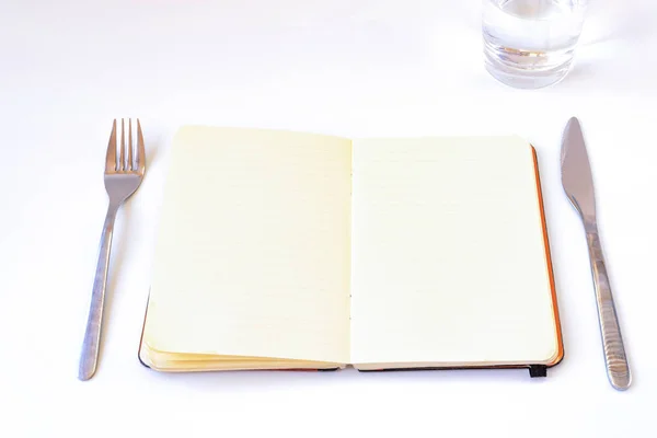 ダイエットのコンセプトです プレート カトラリー 水のガラスのテーブルの上のノートブックを開く白の背景に — ストック写真