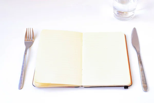 Diyetler kavramı. Tabak, çatal bıçak takımı ve su ile masada açık defter; Beyaz arka plan ile.