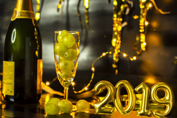 End of the year concept. Glass of champagne with grapes inside, with holiday decoration