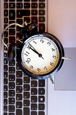 Konsept içinde bilgisayar olma vakti. Siyah çalar saat üstünde laptop.