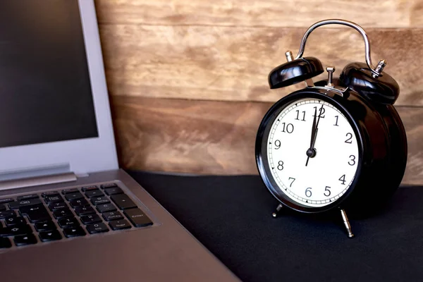 Konsept içinde bilgisayar olma vakti. Siyah çalar saat üstünde laptop.