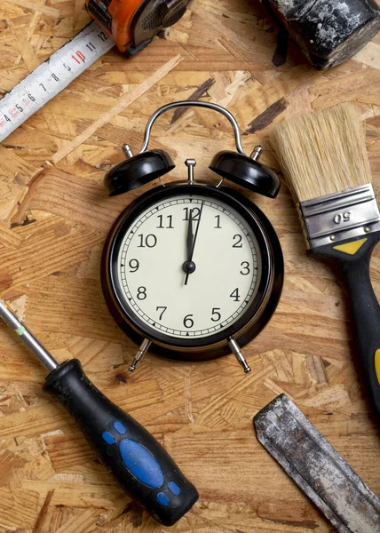 DIY zaman kavramı. Ahşap çalışma masa üzerinde siyah bir çalar saat çevreleyen araçları.