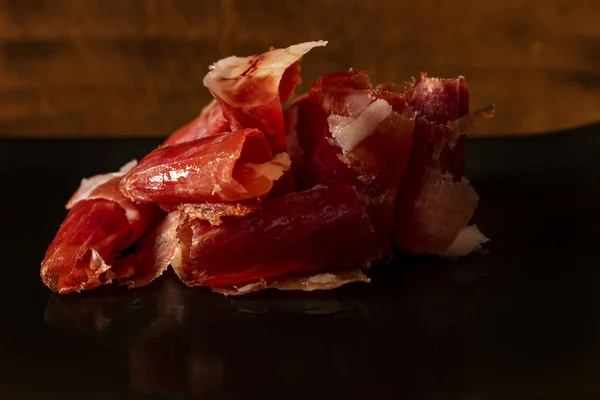 Serrano ham chips on a plate over old wood.