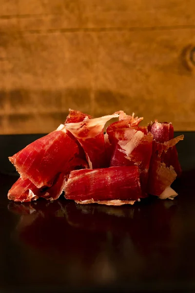 Serrano ham chips on a plate over old wood.