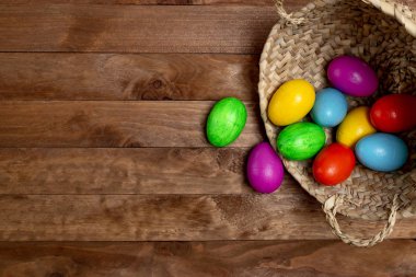 Ahşap bir masa üzerinde bir hasır sepet yumurta farklı renkteki yerleştirilir.