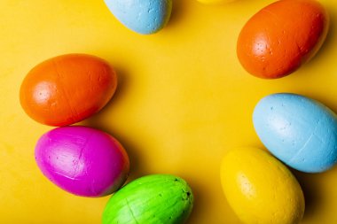 Paskalya yumurtaları sarı bir arka plan üzerinde mavi, sarı, turuncu ve yeşil renk.