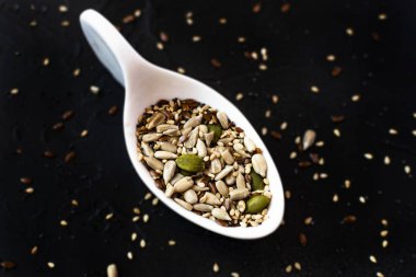 Yanındaki beyaz Seramik kaşık farklı meyve tohumları susam. Karanlık gıda kavramı