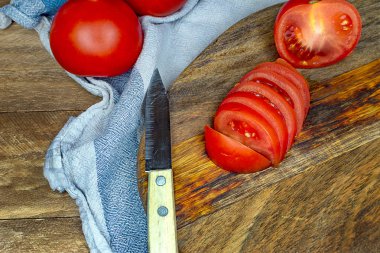 Tahta bir masada bir konserve tabağı içinde dilimlenmiş domates.