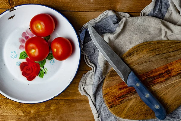 Tomates en rodajas en un plato de hojalata sobre una mesa de madera . — Foto de Stock