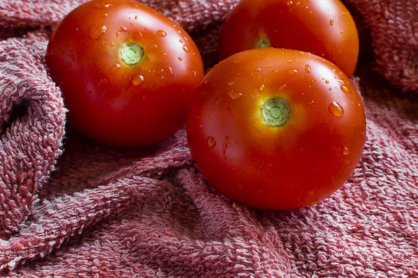 Drei nasse Tomaten auf einem Tuch. — Stockfoto
