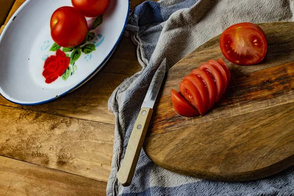Tomates en rodajas en un plato de hojalata sobre una mesa de madera . — Foto de Stock