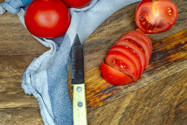 Tomaten in Scheiben geschnitten in einem Blech auf einem Holztisch. — Stockfoto