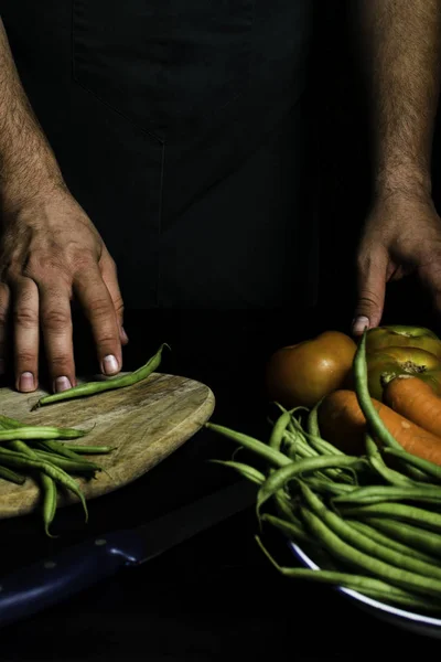 Hombre con delantal verde presentando verduras y verduras de jardín . — Foto de Stock