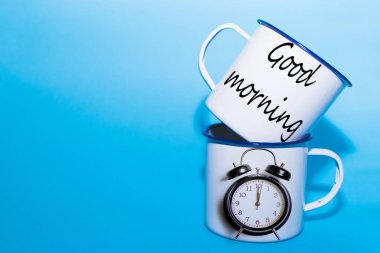 Uyandırma konsepti. Mavi arka plan üzerinde iki metal bardak.