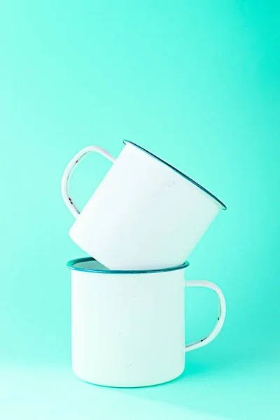 Две белые металлические чашки на голубом фоне . — стоковое фото