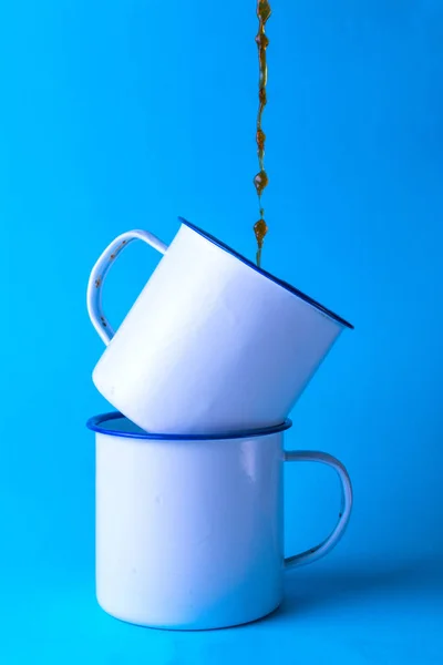Кофе падает на две белые металлические чашки . — стоковое фото
