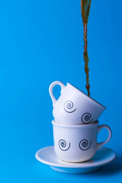 Café cayendo en dos tazas de cerámica blanca . — Foto de Stock