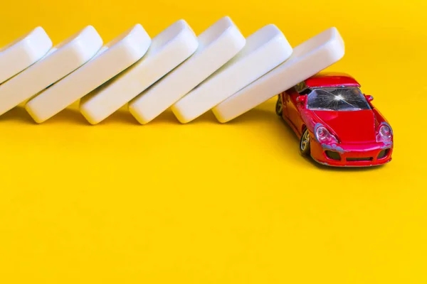Araba sigortası konsepti. Kırmızı bir arabanın üzerine düşen domino taşları.