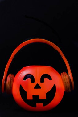 Turuncu kulaklık ve siyah arka plan ile Halloween kabak.