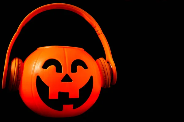 Calabaza de Halloween con auriculares naranjas y fondo negro . —  Fotos de Stock