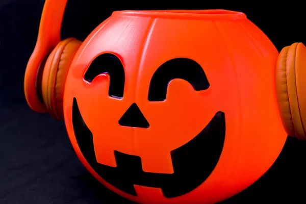 Calabaza de Halloween con auriculares naranjas y fondo negro . —  Fotos de Stock