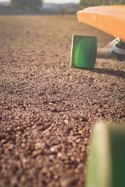 Green wheels of penny board on red asphalt to skate. — Stock Photo, Image