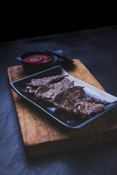 Bife de carne cortado em tiras com molho de tomate em madeira . — Fotografia de Stock