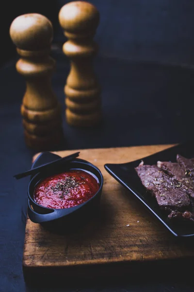 Filete de ternera laminado con salsa de tomate con fondo negro . — Foto de Stock